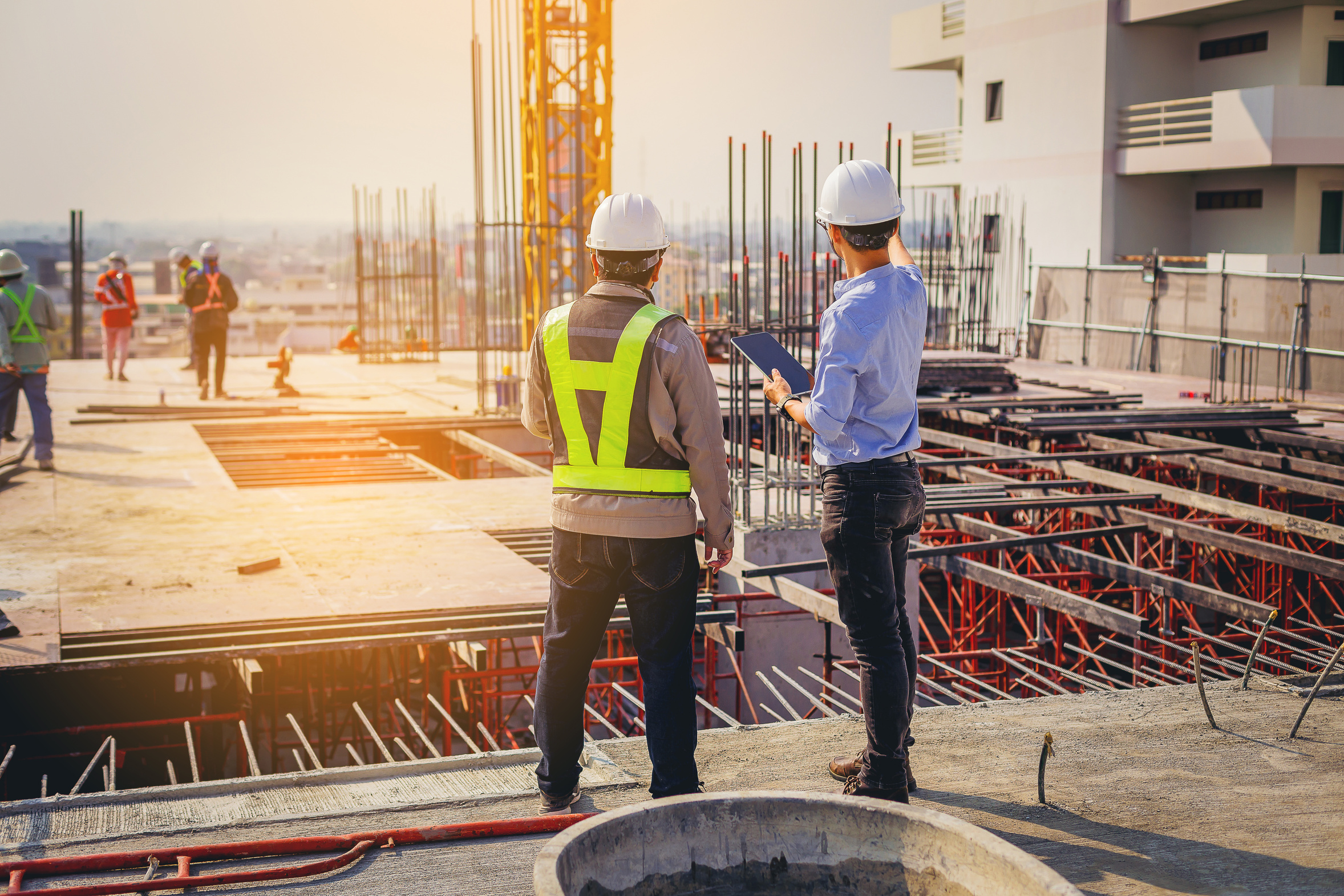 Two men reviewing construction site with tablet